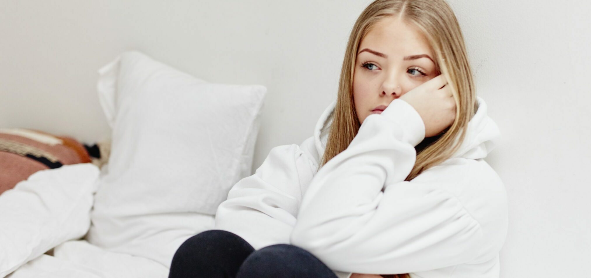 Worried woman sitting in bedroom
