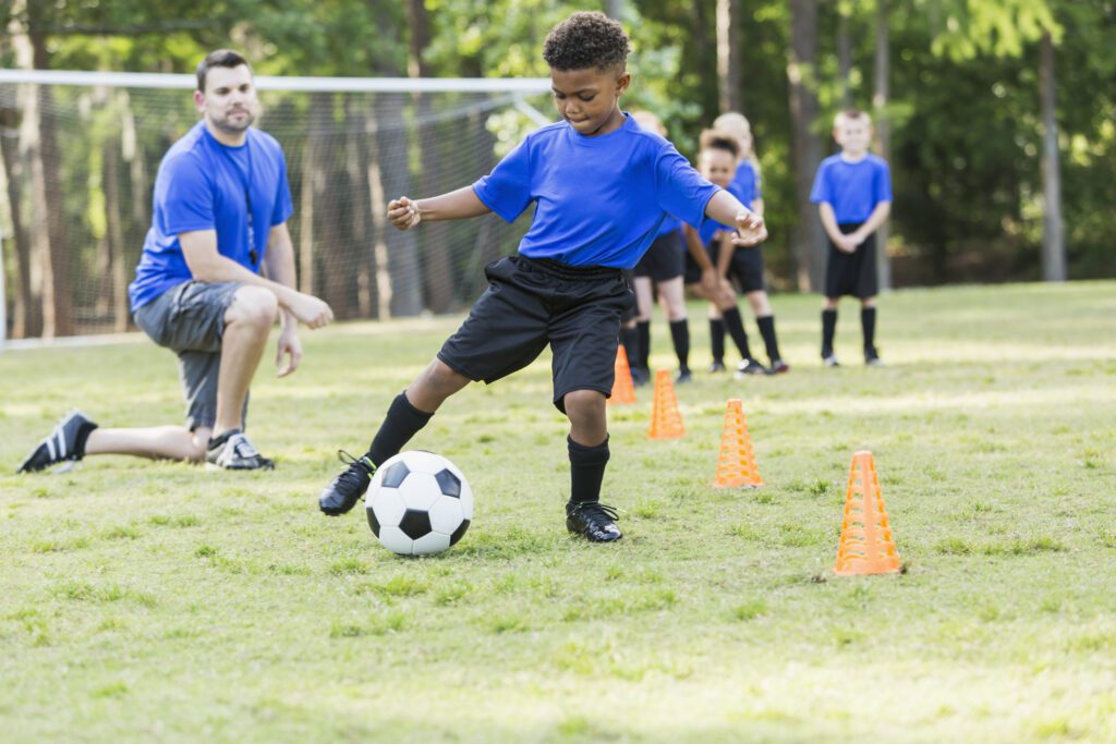Kid training a soccer drill with a coach